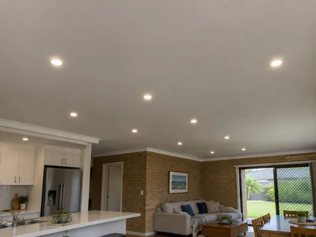 Living room and kitchen with recessed downlights in a brick-walled home interior in Benowa